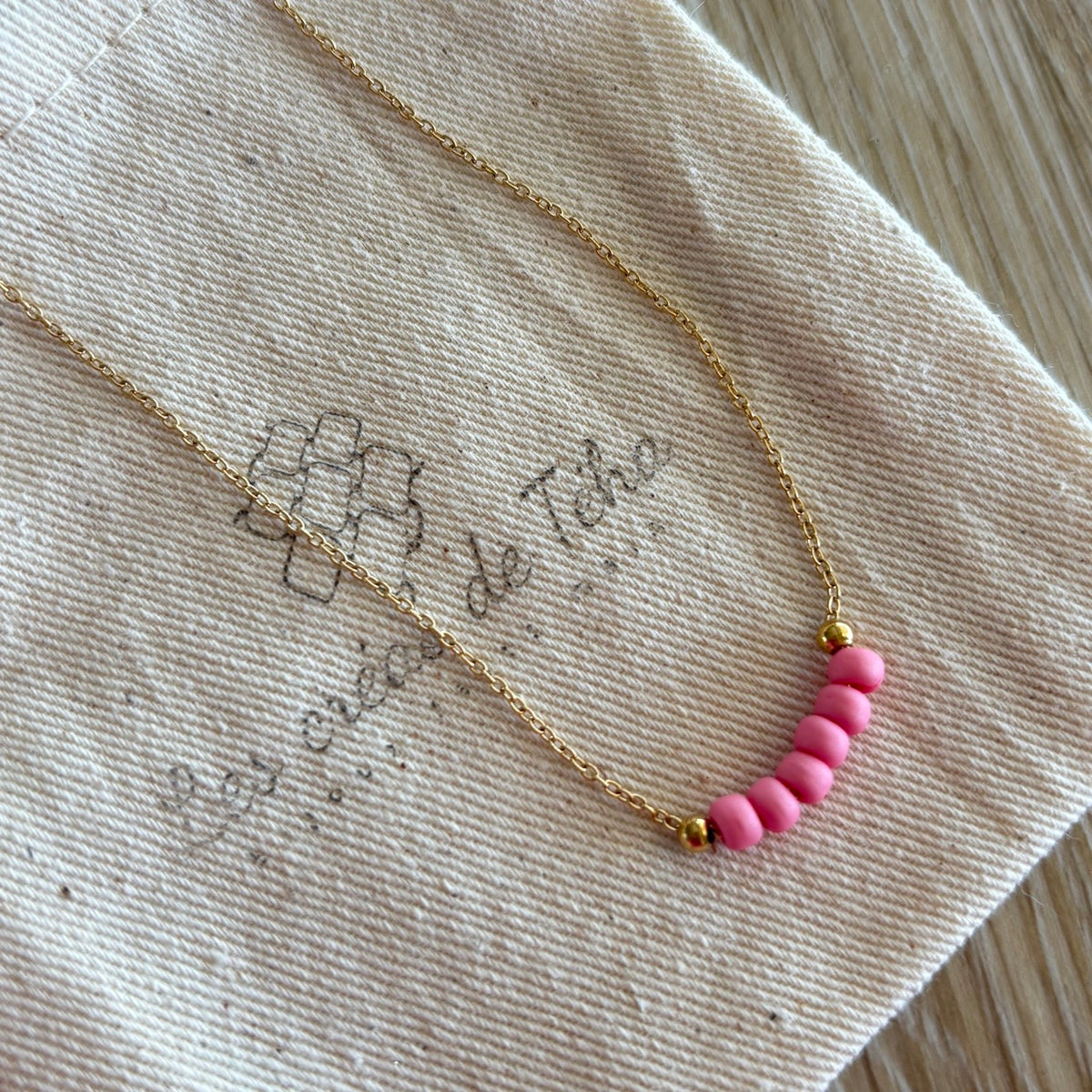 Collier fin en acier inoxydable doré et perles de verre modèle Perla Octobre rose